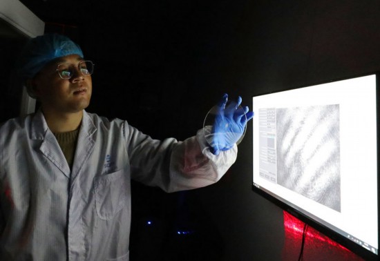 赵苗博士在上海光机所光学实验室向记者展示“超级光盘”（2月29日摄）。