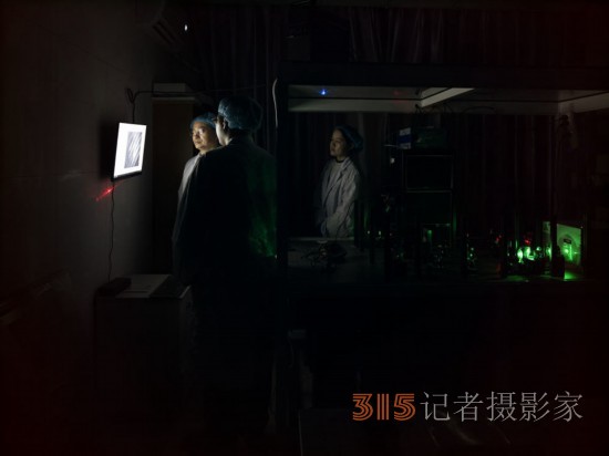阮昊研究员（左）和他的学生赵苗（中）、胡巧在上海光机所光学实验室，利用国际首创的双光束调控聚集诱导发光超分辨光存储技术做写入试验（2月29日摄）。